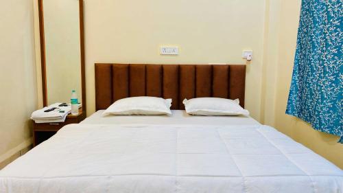 a bedroom with a large white bed with a wooden headboard at Hotel Rewanchal in Godarpura