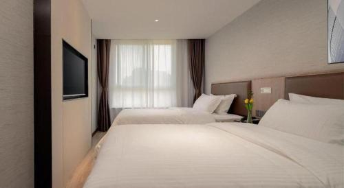 a hotel room with two beds and a television at GreenTree Inn Ganzhou Sankang Temple DaRunFa Express Hotel in Ganzhou