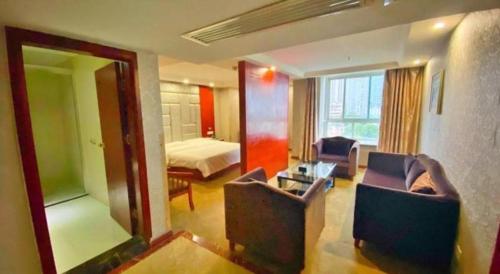 a room with two chairs and a bed and a mirror at GreenTree Inn Ganzhou Sankang Temple DaRunFa Express Hotel in Ganzhou