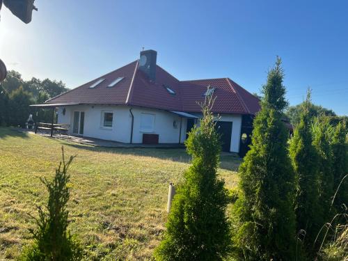 a white house with a red roof and some trees at Sands Dom Szteklin in Szteklin