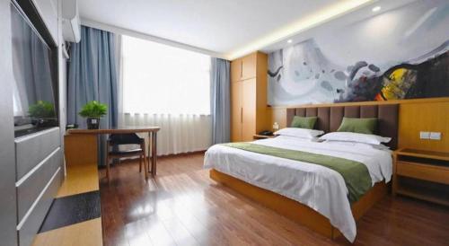 a bedroom with a large bed and a desk at GreenTree Inn Gaoyou Government in Yangzhou