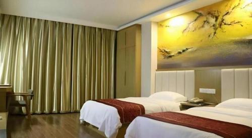 a hotel room with two beds and a painting on the wall at GreenTree Inn Gaoyou Government in Yangzhou