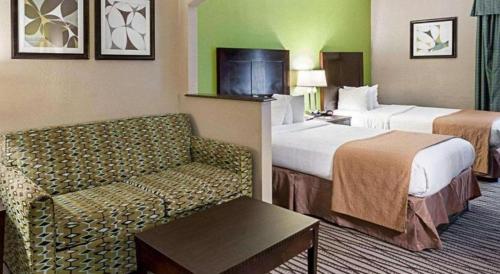a hotel room with two beds and a couch at Quality Suites in Sulphur