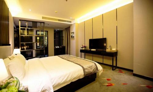 a bedroom with a bed and a desk and a television at Shantou Grandtide Hotel in Shantou