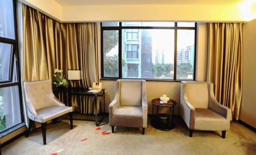 two chairs and a table in a room with windows at Shantou Grandtide Hotel in Shantou