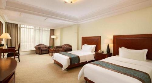 a hotel room with two beds and a desk at Changshu Jinling Tianming Grand Hotel in Suzhou