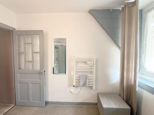 a white room with a door and a mirror at Maison Confortable Proche des Plages in Fleury