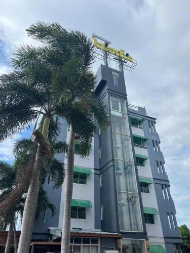 a tall building with palm trees in front of it at Hihotel Saraburi in Sara Buri