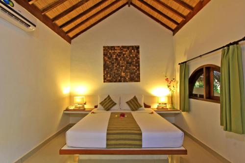 um quarto com uma cama num quarto com 2 candeeiros em Laguna Gili em Gili Trawangan
