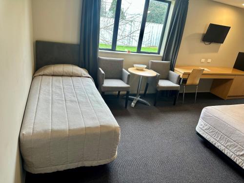 a bedroom with a bed and a desk and chairs at Pokeno Motel in Pokeno