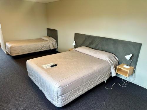a hotel room with two beds and a lamp at Pokeno Motel in Pokeno