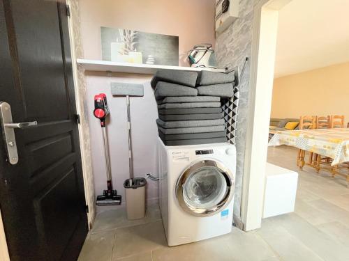 a washing machine in a room with a pile of towels at Maison Confortable Proche des Plages in Fleury