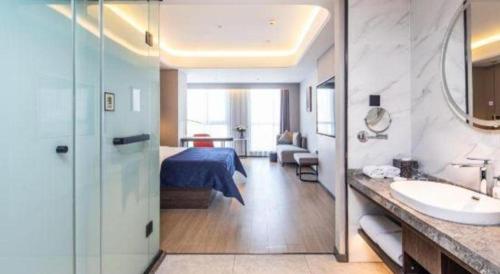a bedroom with a bed and a bathroom with a sink at Yitel Collection Lianyungang High-speed Railway Station Suning Plaza in Lianyungang