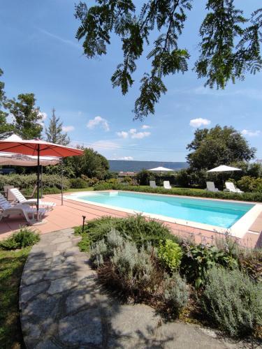 a swimming pool with an umbrella and a table and chairs at Bed&Breakfast Villa Camilla in Ivrea