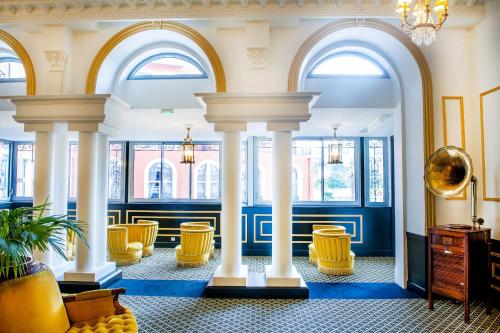 a lobby with columns and chairs and windows at Grand Hotel Gallia & Londres in Lourdes