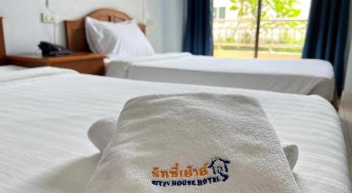 two beds in a hotel room with a towel on them at Ritzy House Hotel in Chumphon