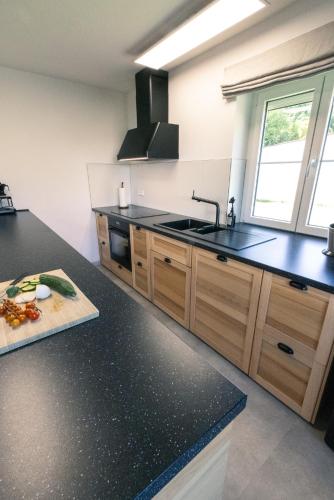 a kitchen with black counter tops and a sink at Landhaus Paco Familienferien mit Sauna und Kamin in Blaufelden
