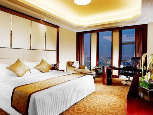 a hotel room with a bed and a desk and windows at Dezhou Regal Kangbo Hotel in Dezhou