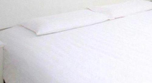 a white bed with white sheets and pillows at City Comfort Inn Wuhan High Speed Railway Station in Wuhan