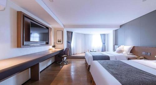 a hotel room with two beds and a television at Zhongshan Louis Hotel in Zhongshan