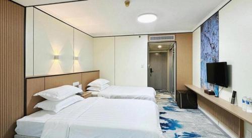 a hotel room with two beds and a flat screen tv at Dalian Bohai Pearl Hotel in Dalian