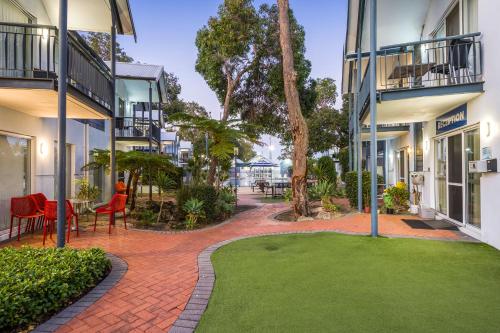 a brick walkway between two buildings with a green yard at Mandurah Quay Resort in Mandurah