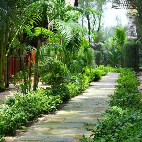 a stone path in a garden with palm trees at HON BA LAGI BEACH RESORT in La Gi