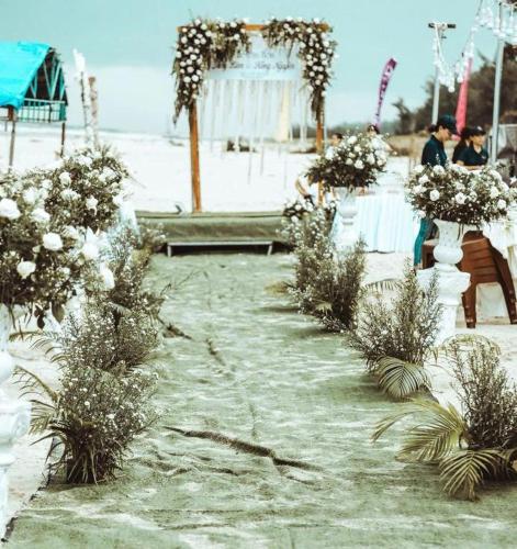 a row of white vases with flowers on a beach at HON BA LAGI BEACH RESORT in La Gi