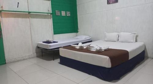 a room with two beds and a bench in it at Bunda House Syariah in Padang