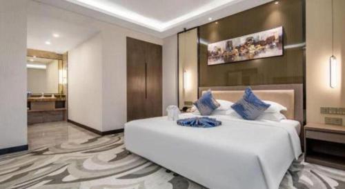 a bedroom with a large white bed with blue pillows at Shaanxi Business Hotel in Shanghai