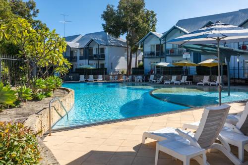 a swimming pool with chairs and umbrellas next to a building at Mandurah Quay Resort in Mandurah