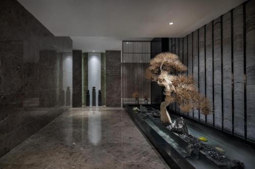 a lobby with a tree in the middle of a room at Yuan Culture Hotel Shenzhen World Shajing in Shenzhen
