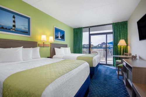 a hotel room with two beds and a balcony at Travelodge by Wyndham Outer Banks/Kill Devil Hills in Kill Devil Hills