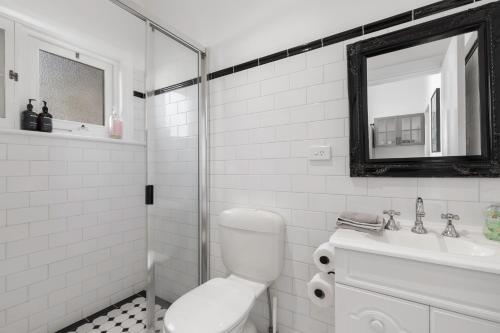 a white bathroom with a toilet and a sink at Bath Street Cottages in Adelaide