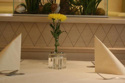 a table with a vase with a yellow flower in it at Parkhotel in Bad Schallerbach