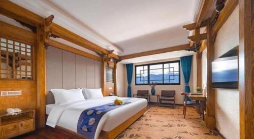 a bedroom with a large white bed in a room at Zhangjiajie Xiangfu International Hot Springs Hotel in Zhangjiajie