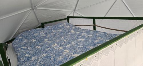a bed in a tent with a blue blanket at Domek nad jeziorem Romantyka in Giże