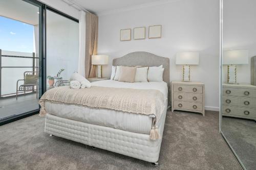 Un dormitorio con una gran cama blanca y un balcón. en Balance at Blair Athol, en Gepps Cross