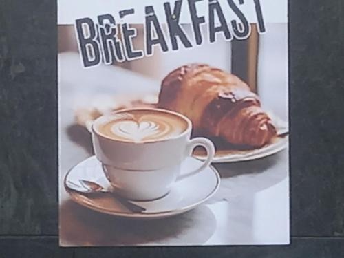 Una revista con una taza de café y un croissant. en Milano City centre PORTA ROMANA SUITE with FREE PARKING GARAGE - newly COZY 2 bedrooms apartment with 2 bathrooms living room fully equipped kitchen and washing machine Smart tv - SUBWAY METRO 3 stops to Duomo, en Milán