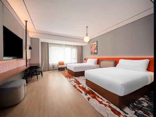 a hotel room with two beds and a flat screen tv at Hilton Garden Inn Taiyuan Jiefang Road in Taiyuan