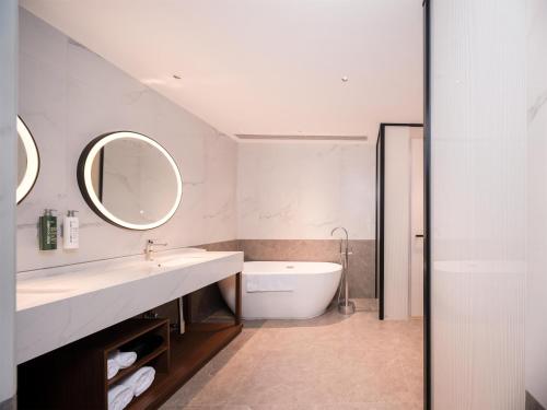 a bathroom with a sink and a tub and a mirror at Hilton Garden Inn Taiyuan Jiefang Road in Taiyuan