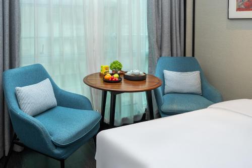 a hotel room with two chairs and a table with fruit on it at Xin'an Yihao Hotel - Near Xiamen Railway Station, near Vientiane City, minibar is free in Xiamen