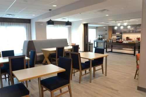 a restaurant with tables and chairs and a kitchen at Hampton Inn Cabot in Cabot