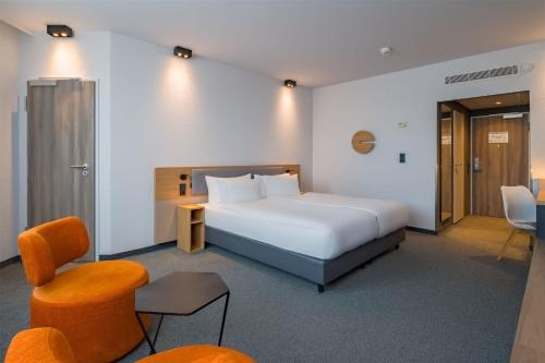 a hotel room with a bed and a chair at Spark by Hilton Wuppertal City Centre in Wuppertal