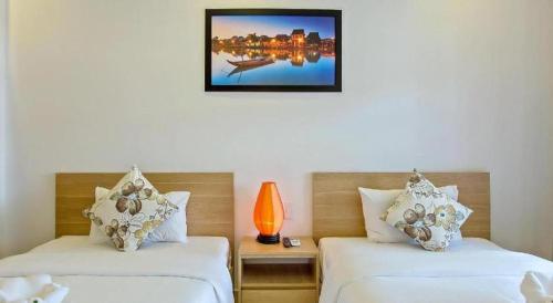 a room with two beds and a picture on the wall at Kim's Villa Hoi An in Hoi An