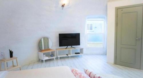 a white living room with a television on a white wall at All That Water Pension in Gapyeong
