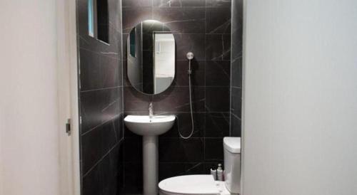 a black tiled bathroom with a sink and a mirror at All That Water Pension in Gapyeong