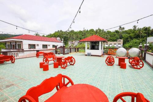 a patio with red chairs and tables and a building at Mayon Backpackers Hostel in Legazpi