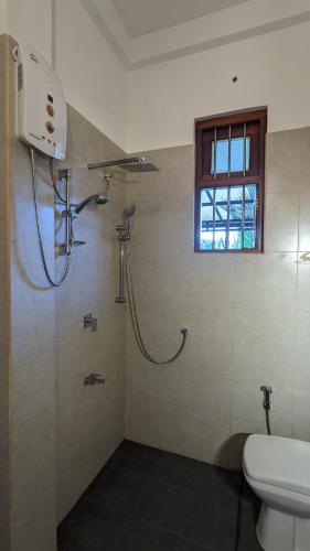 a bathroom with a shower with a toilet and a window at Lake side haven villa in Tangalle