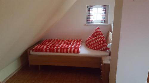 ein kleines Bett mit zwei Kissen unter einem Fenster in der Unterkunft Haus Oltmanns in Quanens